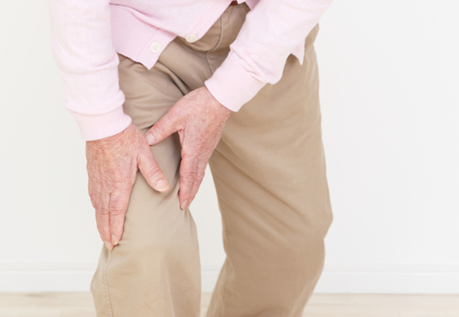 膝に痛みを感じ手をあてる男性